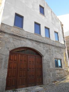 um edifício de pedra com uma porta de garagem de madeira em Coreto Apartments em Sabugueiro