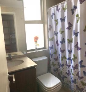 a bathroom with a toilet and a shower curtain with butterflies at Depto Marina Poniente in Viña del Mar