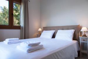 a bedroom with a white bed with towels on it at Villa Panorea in Yénion +29 photos