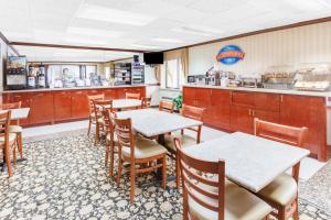 a restaurant with tables and chairs and a kitchen at Baymont by Wyndham Kalamazoo West in Kalamazoo