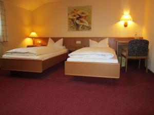 a hotel room with two beds and a chair at Gasthaus Neupert in Lemberg