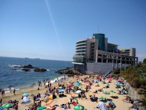 una multitud de personas en una playa con un edificio en Bello Departamento Viña, en Viña del Mar