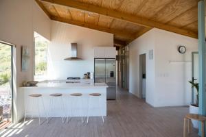 a kitchen with a white island and stools at Hahei Ocean Dream in Hahei