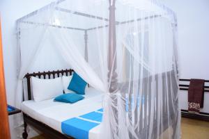 1 dormitorio con cama con dosel y almohadas azules en Kabalana Design House Villa, en Ahangama