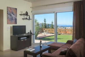 un soggiorno con TV e ampia finestra di Dreamcatcher Villa a Pastida