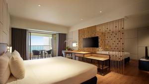 a hotel room with a bed and a desk and a television at PARKROYAL Penang Resort in Batu Ferringhi