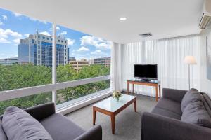 a living room with a couch and a large window at Park Regis Griffin Suites in Melbourne