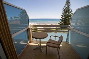 balkon ze stołem, krzesłem i plażą w obiekcie Hotel Garden Lido w mieście Loano