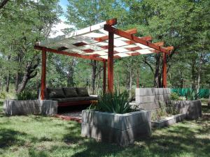 a bench under a wooden pergola in a yard at Alma Serrana Apart Cabañas - Solo Adultos in Nono