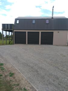 a building with four garage doors on a gravel driveway at Barberry Hill in Stratford