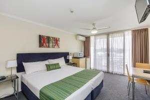 a hotel room with a large bed and a desk at The Wellington Apartment Hotel in Brisbane