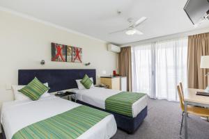 a hotel room with two beds and a desk at The Wellington Apartment Hotel in Brisbane