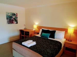 a hotel room with a bed with two towels on it at Rockhampton Palms Motor Inn in Rockhampton