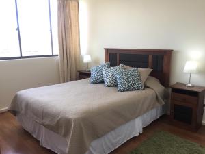 Un dormitorio con una cama con almohadas. en Departamento 8 Norte, Torre del Mar, en Viña del Mar