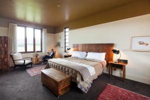 - une chambre avec un lit et une personne assise dans une chaise dans l'établissement Hapuku Lodge & Tree Houses, à Hapuku