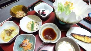 una tavola con piatti di cibo su un tavolo di Onyado Hishiya Torazo a Yamanouchi Altre 37 foto