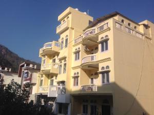 ein hohes gelbes Gebäude mit weißen Balkonen darauf in der Unterkunft Seventh Heaven Inn Rishikesh in Rishikesh