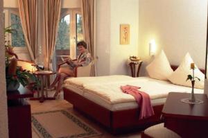 a woman sitting on a bed in a room at Hostellerie Bacher in Neunkirchen
