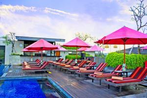 a group of chairs and umbrellas next to a pool at Sevn Legian in Legian