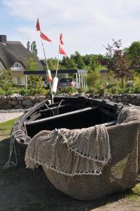 a wooden boat with two flags in a yard at Reethus am Strand - Haushälfte 2 mit Kamin, Sauna in Lobbe