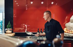 a man cooking in a kitchen with wine bottles at Hinterwies – Ski In / Lodge / Dine in Lech am Arlberg