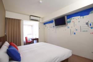 um quarto de hotel com uma cama e uma televisão na parede em In One City Inn em Taichung