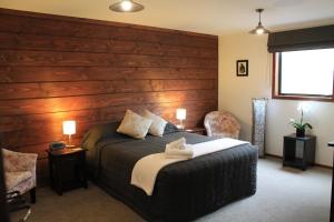 Inn the Bay Bed & Breakfast في كايكورا: غرفة نوم بسرير مع جدار خشبي