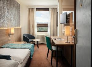 a hotel room with a desk and a bed and a table at Congress & Wellness Hotel Olsanka in Prague