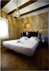Un dormitorio con una cama grande en una pared de piedra. en Apartamentos Doña Candida, en Valderrobres