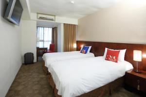 a hotel room with two beds and a television at In One City Inn in Taichung