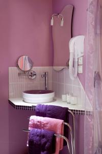 a bathroom with purple walls and a sink and towels at La Gourmandine in Châtellerault