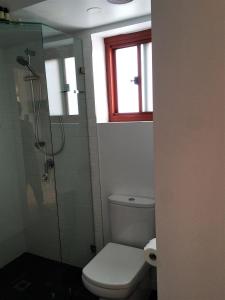 baño con aseo y ducha y ventana en Byron Beach House, en Byron Bay