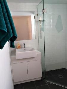 y baño con lavabo y ducha acristalada. en Byron Beach House, en Byron Bay