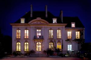 een groot wit huis met lichten aan bij La Gourmandine in Châtellerault