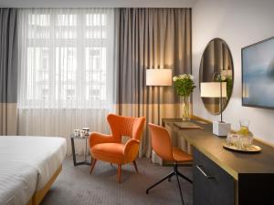 a hotel room with a bed and a desk and chairs at K+K Hotel Fenix in Prague