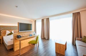 Habitación de hotel con cama y escritorio con TV. en Vital Hotel an der Therme GmbH, en Bad Windsheim