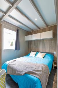 a bedroom with a large bed with blue sheets at Camping White Rock in Castellane