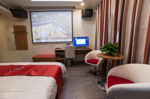 a hotel room with a tv and a bed and a desk at Thank Inn Chain Hotel Jiangsu Wuxi Xishan District Leather City in Dongbeitang
