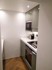 a small kitchen with a stove and a microwave at Modern 1 Bedroom Apartment in Kensington in London