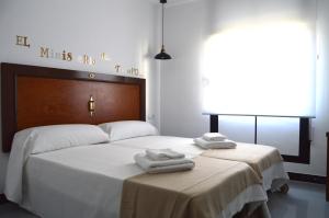 1 dormitorio con 2 camas, sábanas blancas y toallas en Ohana Apartamento Rural, en Malón