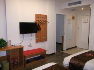 ein Schlafzimmer mit einem Bett und einem TV an der Wand in der Unterkunft Thank Inn Chain Hotel Shandong Binzhou Wudi Pedestrian Street in Wudi