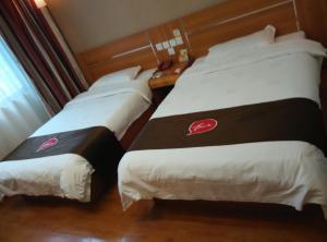 duas camas sentadas uma ao lado da outra num quarto em Thank Inn Chain Hotel Jiangxi Yichun Fengxin East Fengchuan Road Huangni Lane em Fengxin