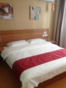 uma cama com um cobertor vermelho e branco em Thank Inn Chain Hotel Hebei Langfang the 6th Street em Langfang