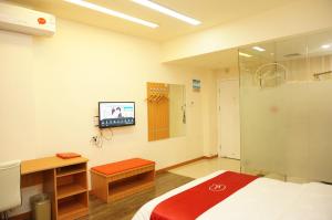 Habitación hospitalaria con cama y TV en la pared en Thank Inn Chain Hotel Hunan Loudi New Huaxuefu Road en Dongling
