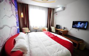 a bedroom with a red and white bed and a television at Thank Inn Chain Hotel Guizhou Anshun Development Area Xihang Road in Anshun