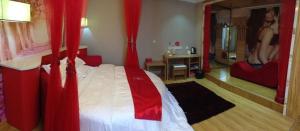 Schlafzimmer mit einem Bett mit roten Vorhängen in der Unterkunft Thank Inn Chain Hotel Henan Xuchang Railway Station Qiyi Road in Xuchang