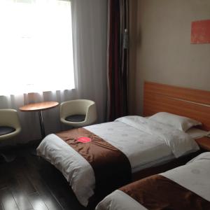 a hotel room with two beds and a table and a window at Thank Inn Chain Hotel Guizhou Anshun Development Area Xihang Road in Anshun