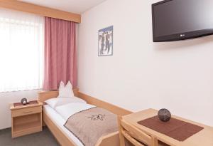 1 dormitorio con 1 cama y TV en la pared en Gasthof Huber, en Braies