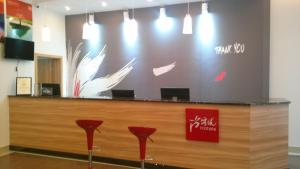 a reception desk with red chairs in a lobby at Thank Inn Chain Hotel Jiangxi Fuzhou Linchuan District Laowuhuang Palace Bus Station in Fuzhou