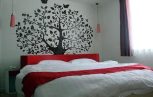 Un dormitorio con una cama roja con un árbol en la pared en Thank Inn Chain Hotel Hebei Cangzhou Qing County Jingfu Avenue, en Qing